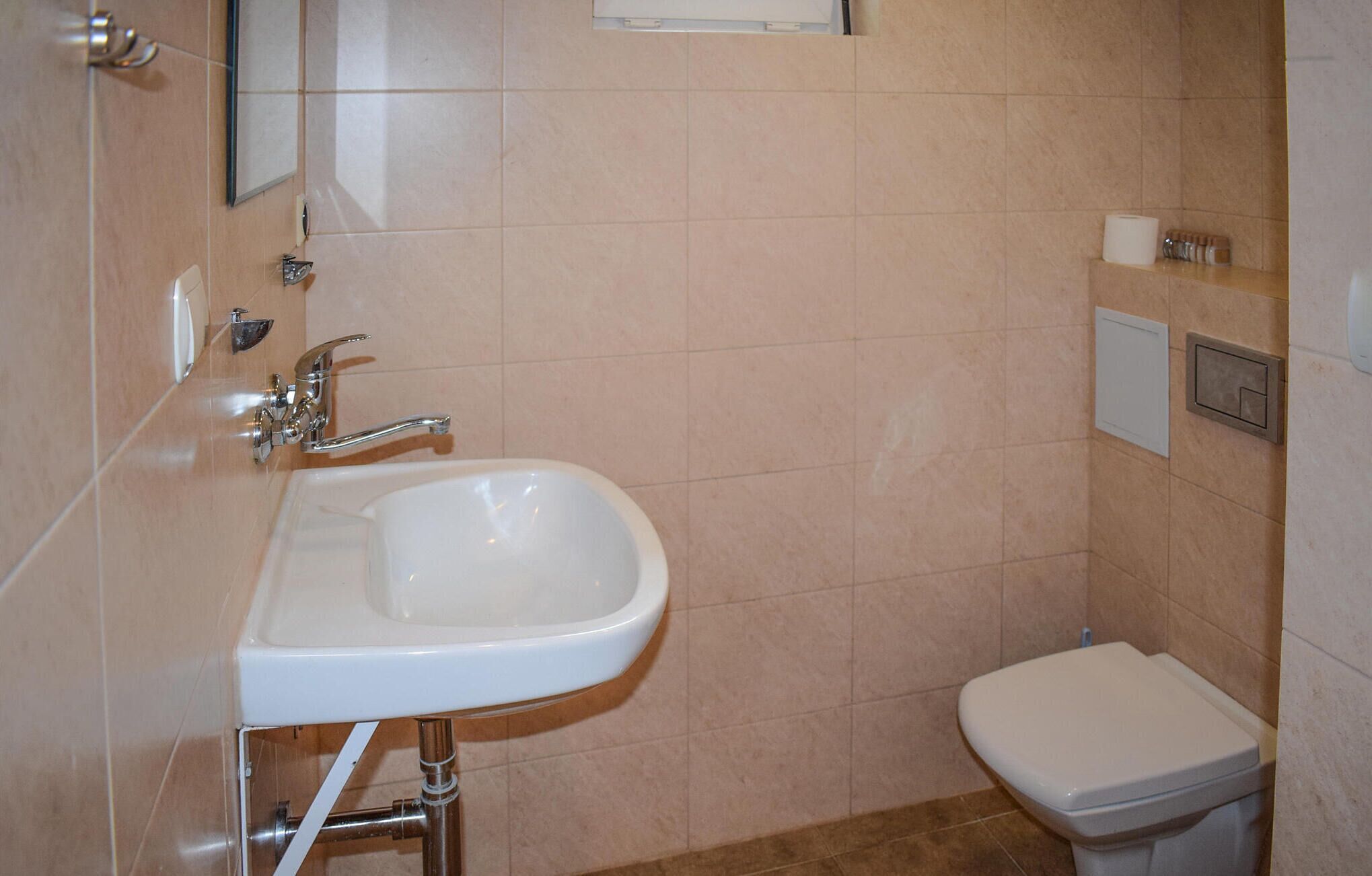 Un baño con lavamanos blanco, inodoro y espejo.