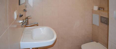 Un baño con lavamanos blanco, inodoro y espejo.