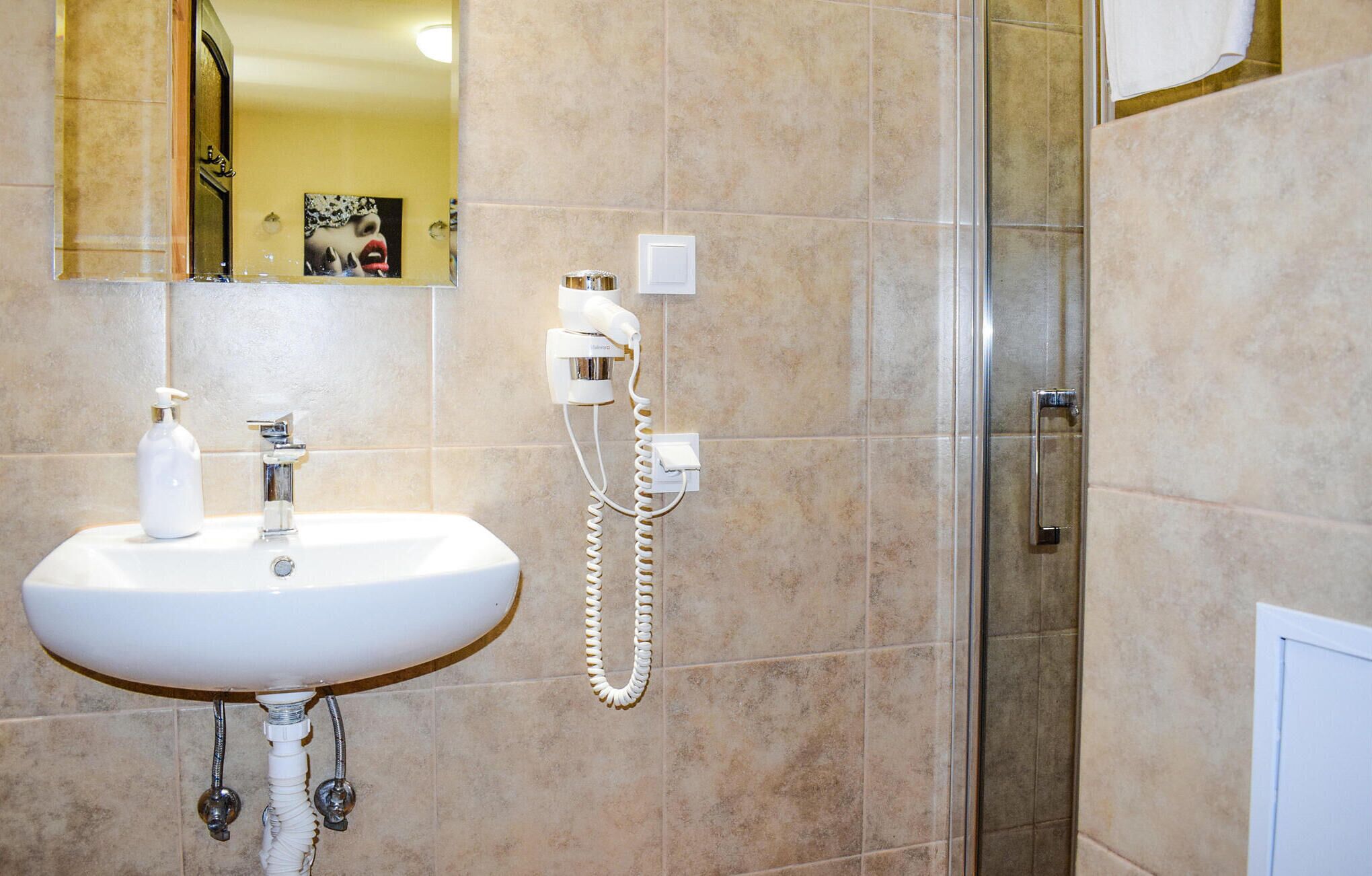 Une salle de bain avec un lavabo blanc, un miroir, une douche et un téléphone.