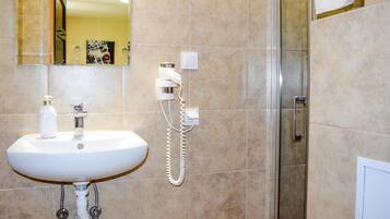 Une salle de bain avec un lavabo blanc, un miroir, une douche et un téléphone.