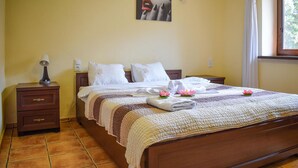 A neatly made bed with a quilt, pillows, and towels, a wooden nightstand with a lamp, and a painting on the wall. - Beautiful apartment in Rydzewo with WiFi (Rydzewo)