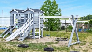 A playground with a slide, swings, and a climbing structure. - Beautiful apartment in Rydzewo with WiFi (Rydzewo)