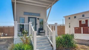 Ein zweistöckiges Haus mit Veranda, Treppe und einem umzäunten Garten.