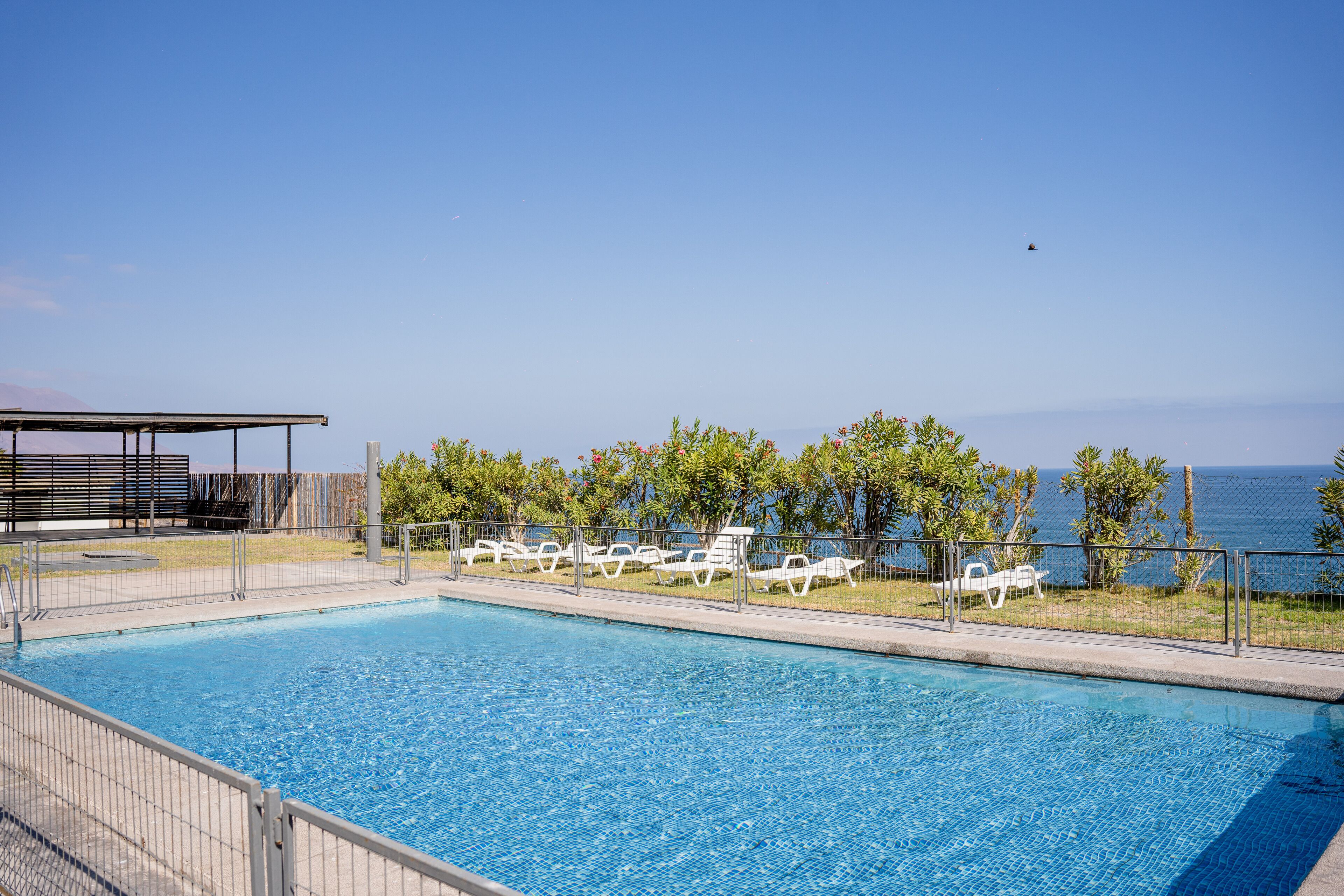 A swimming pool with lounge chairs and a view of the sea.