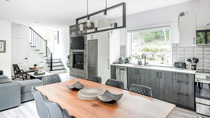 Une cuisine moderne dotée d’un îlot central, d’appareils électroménagers intégrés et d’une grande fenêtre offrant une vue sur l’extérieur.