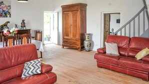 A living room with a wooden floor, red leather sofas, a wooden cabinet, and a vase. - 3 bedroom awesome home in Razac-de-saussignac (razac-de-saussignac)