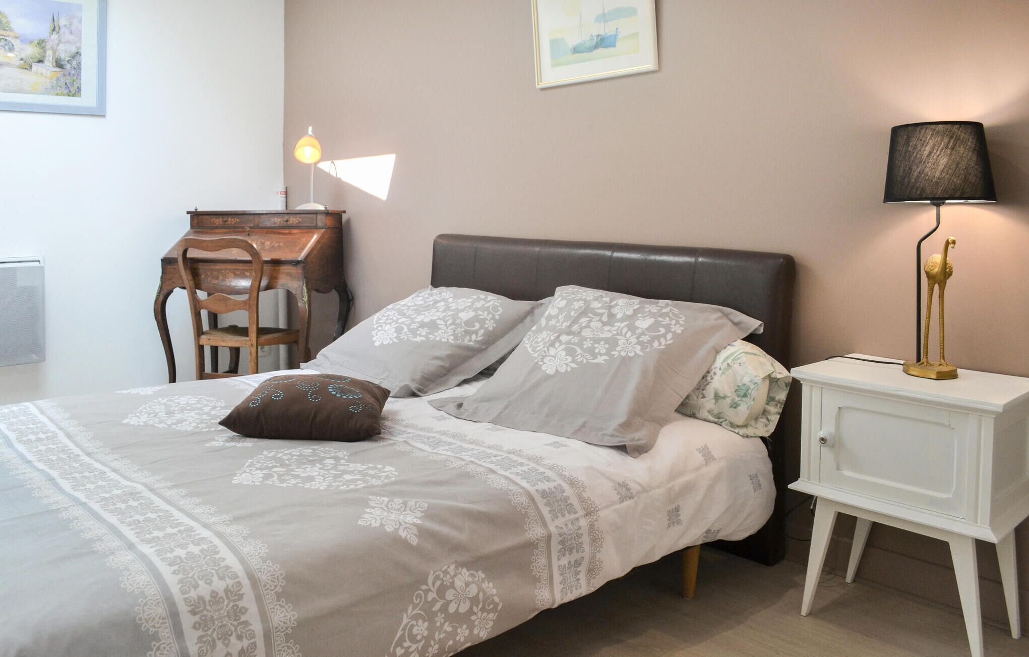 Une chambre à coucher avec un lit, un bureau, une chaise, une lampe et une table de chevet.