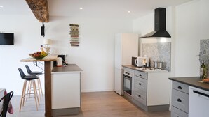 A modern kitchen with a central island, a built-in oven, and a microwave. There are bar stools and a coffee machine on the island. - 3 bedroom awesome home in Razac-de-saussignac (razac-de-saussignac)