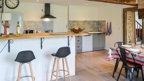 A modern kitchen with a central island, bar stools, and a dining area with a table set for two. - 3 bedroom awesome home in Razac-de-saussignac (razac-de-saussignac)