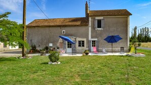 A two-story house with a tiled roof, a chimney, and a small garden with outdoor furniture. - 3 bedroom awesome home in Razac-de-saussignac (razac-de-saussignac)