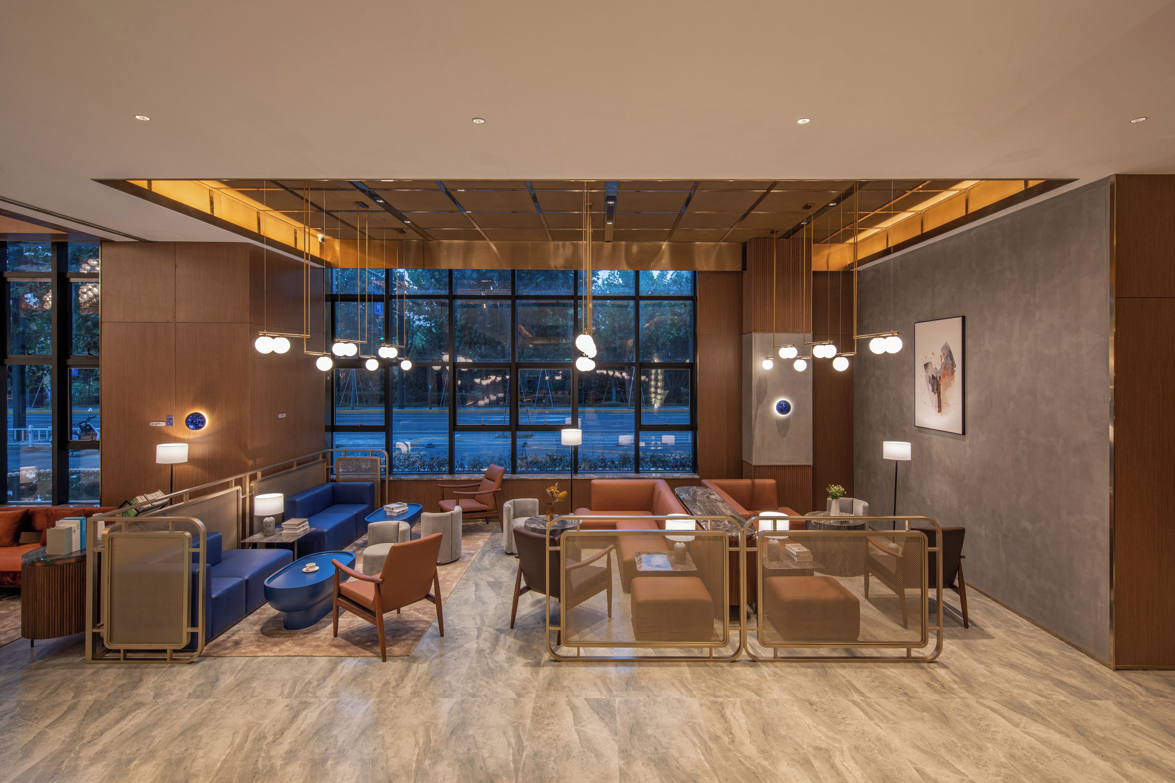 A modern hotel lobby with seating areas, large windows, and contemporary lighting fixtures.