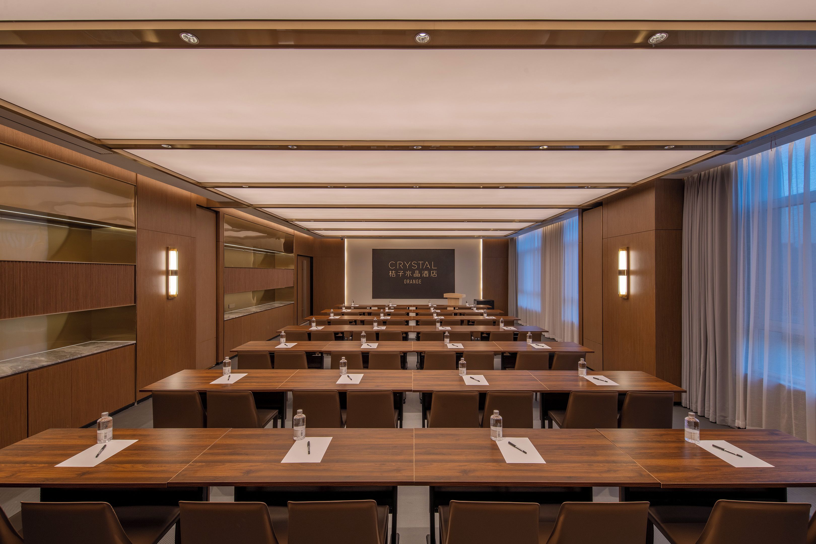 A conference room with multiple tables, chairs, and a projection screen displaying "CRYSTAL ORANGE."