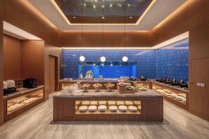 A modern breakfast bar with a central island, wooden paneling, and a blue-tiled backsplash. - Crystal Orange Hotel Yancheng Municipal Government (Yancheng)
