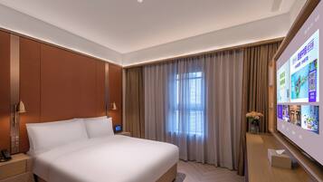 Une chambre d’hôtel moderne avec un grand lit, une table de chevet avec une lampe, un écran de télévision et une fenêtre avec des rideaux.
