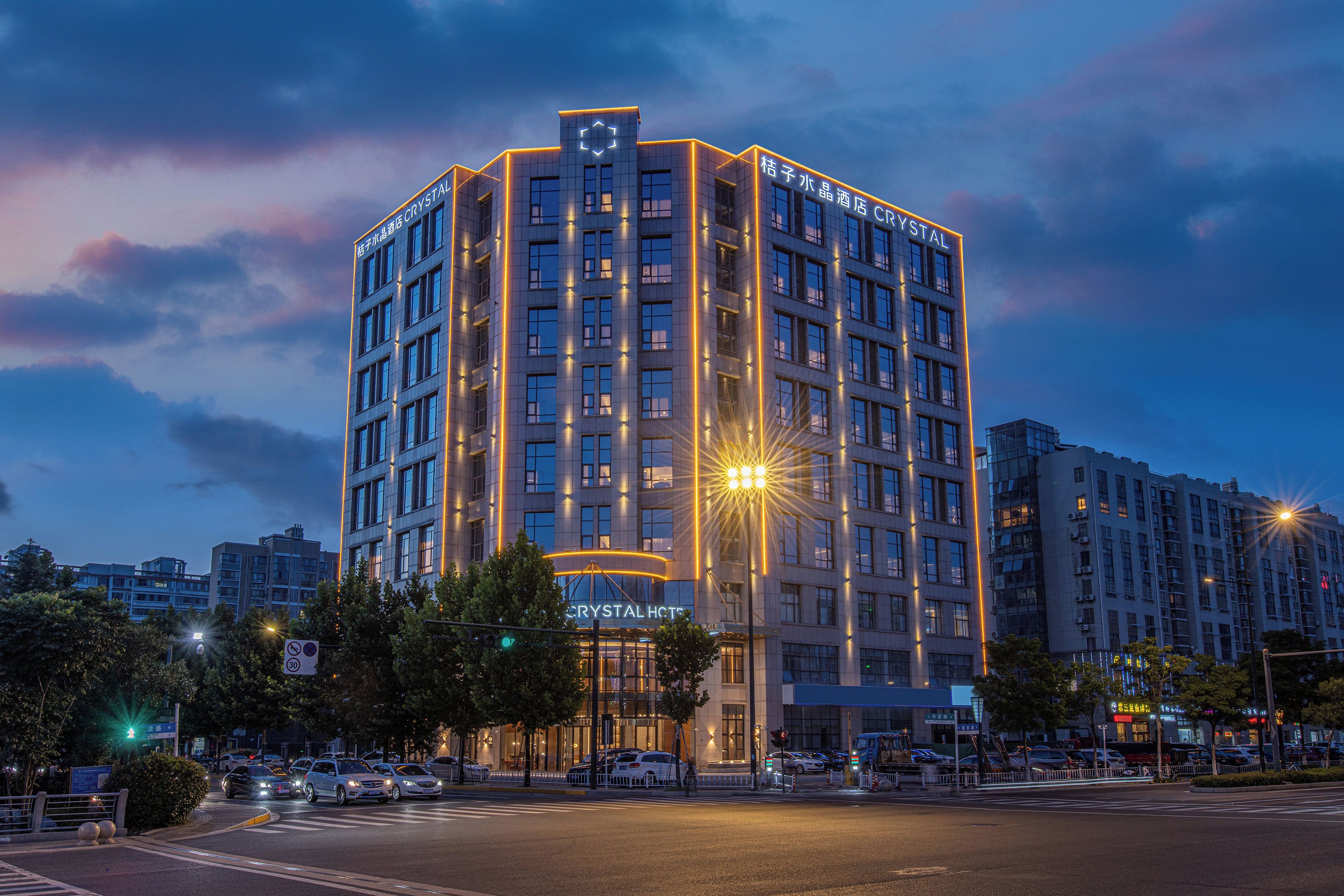 A multi-story hotel with a prominent "CRYSTAL" sign, featuring a modern architectural design with a central light fixture and multiple windows.
