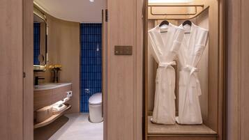 Une salle de bain moderne avec un meuble-lavabo en bois, des toilettes et un espace douche doté d’une porte en verre bleue.