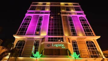 A hotel with a classic architectural design, featuring large arched windows and a prominent sign displaying the name "Logistic Hotel".