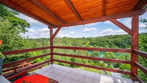 Une terrasse en bois avec un sol carrelé, une table rouge et un banc.