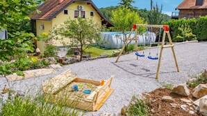 Un quartier résidentiel avec une maison jaune, un terrain de jeux recouvert de gravier et une piscine.