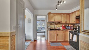 A kitchen with wooden cabinets, a stove, and a microwave. There is a window with a view of the outside. - Cozy home with office walking distance to beach (Rochester)