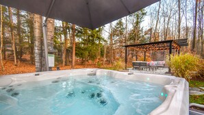 Ein Whirlpool inmitten bewaldeter Landschaft mit einer Pergola und Gartenmöbeln.