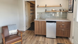 A compact kitchen with wooden cabinets, a built-in dishwasher, and a small countertop. - Springdale Farm & Views - the Gorge, Downtown, Mt. Hood (Troutdale)