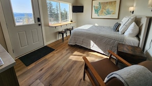 A bedroom with a bed, a desk, a chair, a map on the wall, and a view of the outdoors through a window. - Springdale Farm & Views - the Gorge, Downtown, Mt. Hood (Troutdale)