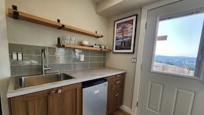 A kitchen with wooden cabinets, a stainless steel sink, and a dishwasher. There is a window with a view of a landscape. - Springdale Farm & Views - the Gorge, Downtown, Mt. Hood (Troutdale)