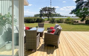 Relax on the deck with wicker furniture and enjoy the serene view of the water, tree, and surrounding field.
