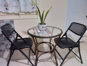A small round table with a potted plant and a magazine, flanked by two black chairs. - Comfortable Stay  (Kingston)