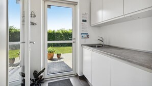 A modern kitchen with white cabinets, a stainless steel sink, and a door leading to a garden. - Gorgeous home in Tarm with WiFi (Tarm)
