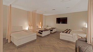 Quarto de hotel com uma cama, dois sofás, uma mesa pequena e uma televisão.
