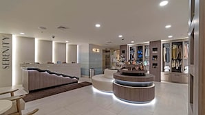 Um hall de hotel moderno com balcão de recepção, área de estar e exposição de roupas.