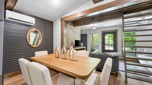 A dining area with a wooden table and white chairs, a stone wall, and a view of the outdoors. - Creek Swimming Boulder Hot Tub Close Buffalo River (Marshall)