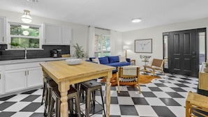 Une cuisine moderne avec des meubles blancs, une table à manger en bois et un sol à carreaux.