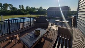 A deck with a pool, outdoor furniture, and a dog. - Residential Home 3 miles from Brennand Airport and 20 miles from EAA.  (Oshkosh)