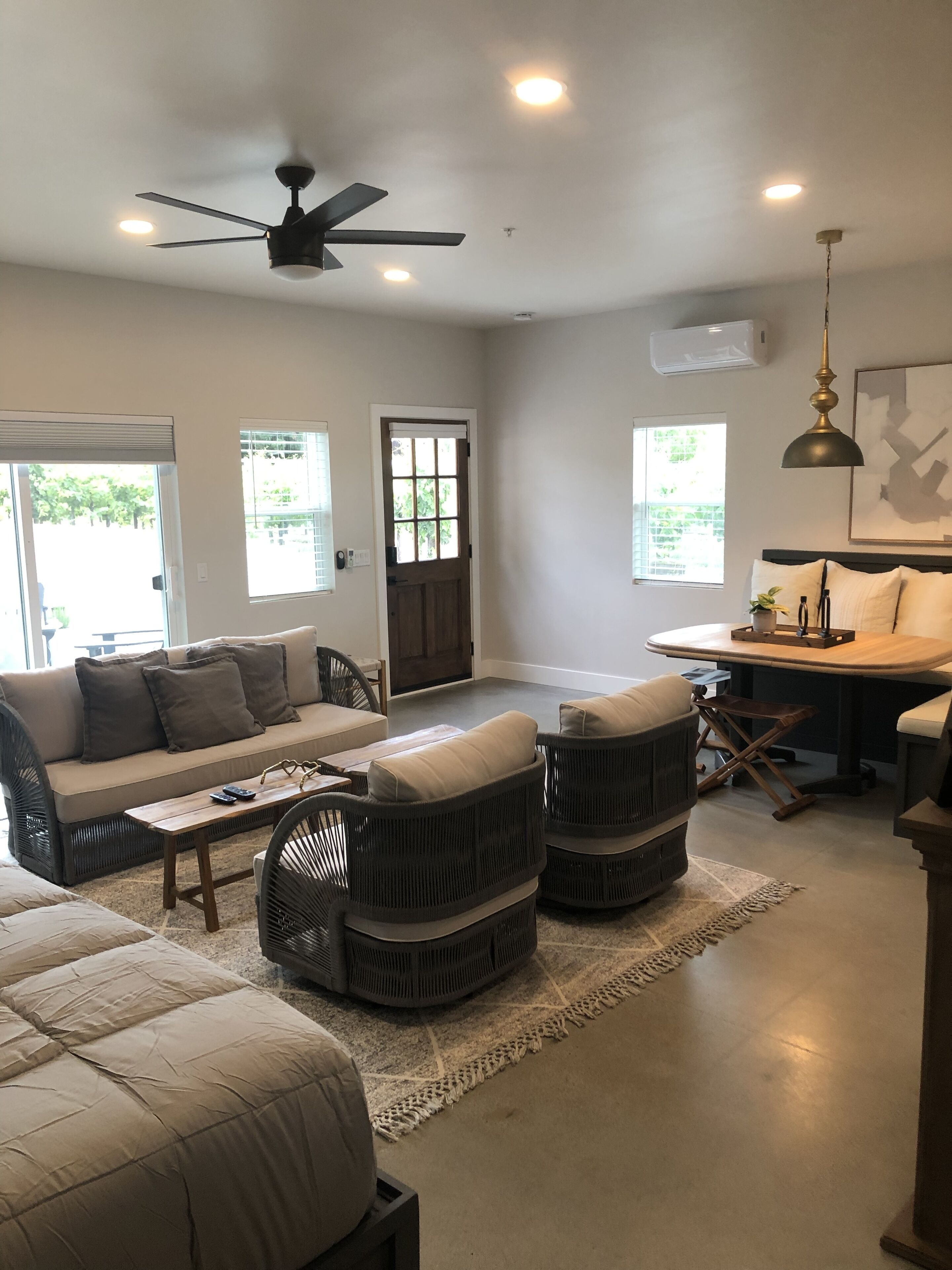 A spacious living room with a sofa, two armchairs, a coffee table, and a dining area with a table and chairs.