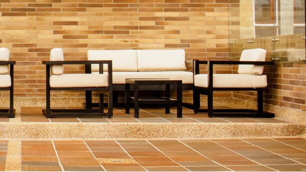 A reception area with a 'WELCOME' sign, a brick wall, and seating arrangements. - Orange by Wellcome (Bogotá)
