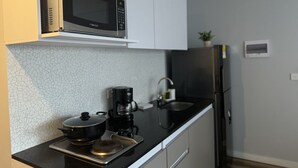 A compact kitchen with a microwave, coffee maker, and a small sink. - Orange by Wellcome (Bogotá)