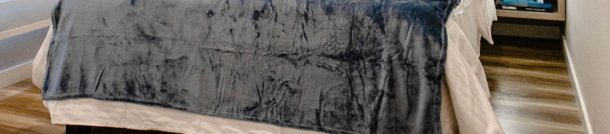 A room with a bed covered in a dark, textured blanket.