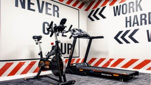 A gym with exercise equipment, motivational wall text, and a red and white striped floor. - Orange by Wellcome (Bogotá)