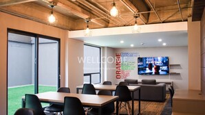 A modern office space with a large window, conference tables, and a motivational wall. - Orange by Wellcome (Bogotá)