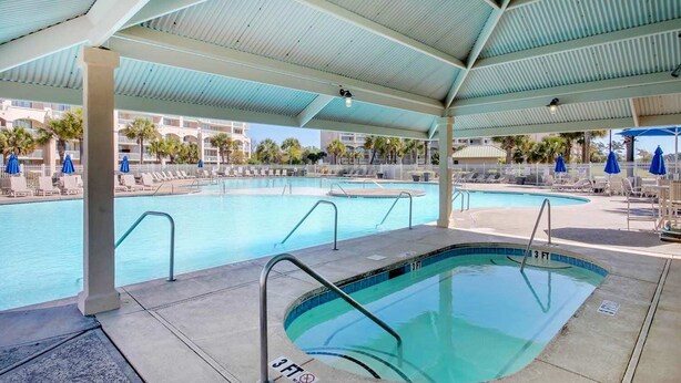 Un espace piscine comprenant une partie couverte et un jacuzzi séparé, tous deux dotés d’indications claires de la profondeur.