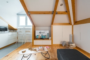 Cozy guest room with a kitchenette, dining area, and seating space, featuring a large window with an outside view.