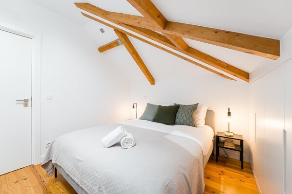 Ein Schlafzimmer mit einem Bett, Kissen, einem Nachttisch und einem Handtuch auf dem Bett.