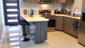 A modern kitchen with a central island, stainless steel appliances, and wooden cabinetry. - Comfy Beds-Pool-Clean Getaway-2 mins to Ocho Rios (Ocho Rios)