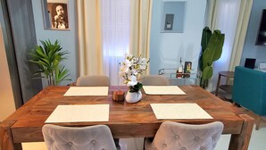 A dining area with a wooden table, four upholstered chairs, a vase with white flowers, and a small plant. - Comfy Beds-Pool-Clean Getaway-2 mins to Ocho Rios (Ocho Rios)