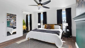 Een moderne hotelkamer met een groot bed, een plafondventilator en uitzicht op de stad.