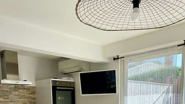 Une cuisine moderne avec un coin repas, un téléviseur et une grande fenêtre.