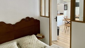 Une chambre avec un lit en bois, un ventilateur de plafond et une vue sur la cuisine.